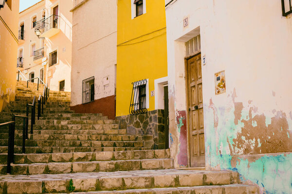 Narrow street in the old town with colored houses with shabby plaster and cobblestone stairs. Finestrat, Spain.