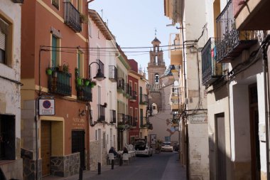Finestrat, Alicante, İspanya - 23 Şubat 2019: Kilise ile meydanına bakan yıpranmış alçı ile renkli evler ile eski şehirde dar sokak