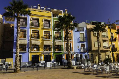 Villajoyosa, İspanya - 3 Temmuz 2018: Güneşli bir günde Villajoyosa'da sokakta kafe, renkli evler ve palmiyeler