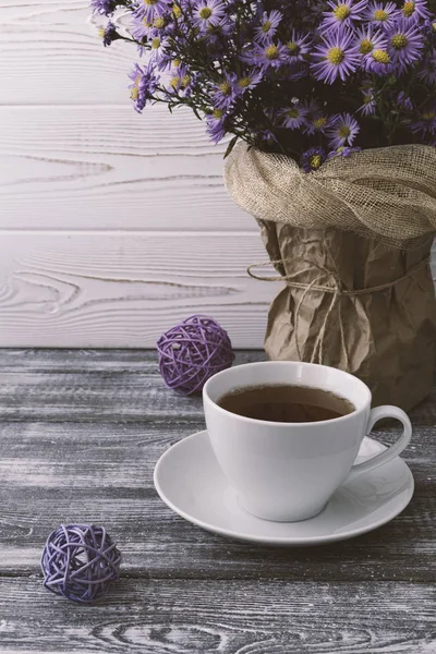 Романтическая осенняя композиция с чашкой чая, сиреневые цветы в вазе на сером деревянном столе. Осенняя концепция . — стоковое фото