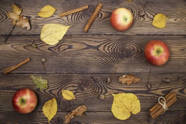 Elma ve düşmüş sonbahar yaprakları üst görünümü, tarçın ahşap bir arka plan üzerinde sopalarla. Mutlu Şükran ve Hasat Günü