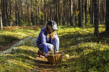 Genç kız yaz veya sonbahar ormanda bir yürüyüş için mantar toplar.