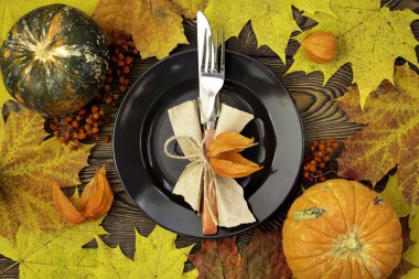 Şükran günü yemeği için sonbahar tablo ayarı. Boş tabak, çatal bıçak takımı, ahşap masa renkli yapraklarda. Sonbahar gıda kavramı.