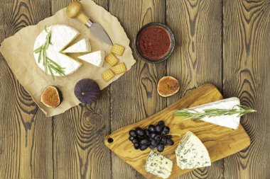 Peynir tabağı reçel, incir, kraker ve otlar ahşap bir arka plan üzerinde servis edilir. Metnin altına yerleştirin. Düz yatıyordu.