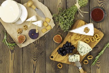 Peynir tabağı reçel, incir, kraker ve otlar ahşap bir arka plan üzerinde servis edilir. Metnin altına yerleştirin. Düz yatıyordu.