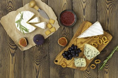 Peynir tabağı reçel, incir, kraker ve otlar ahşap bir arka plan üzerinde servis edilir. Metnin altına yerleştirin. Düz yatıyordu.