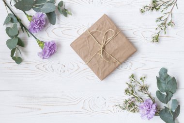 Kraft kağıt ve yukarıdan beyaz masada çiçek hediye veya mevcut kutusu sarılı. Düz styling yatıyordu. Metin için yer kopyalayın.