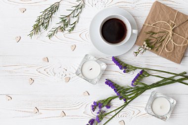 Beyaz ahşap masa üzerinde üstten görünüm kahve, hediyeler, Kalpler, mumlar, çiçekler. Arka plan metin için boş alan ile. Düz yatıyordu