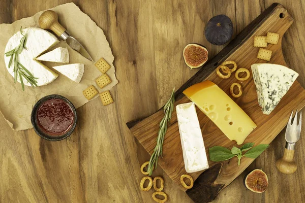 Tasting cheese dish with herbs and fruits on wooden table. Food for wine and romantic, cheese delicatessen. Top view.