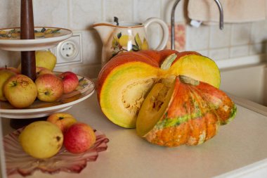 Büyük tohumları ve kırmızı elmaları olan kocaman bir balkabağı mutfaktaki bir meyve tezgahında.