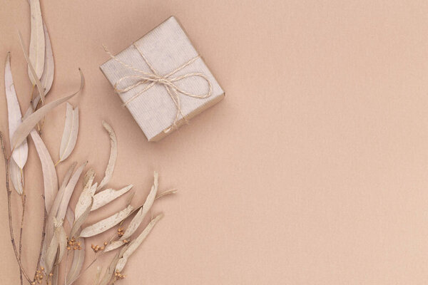 Autumn composition. Gifts wrapped in kraft paper, autumn eucalyptus leaves, on a beige background. Flat lay, top view, copy space.