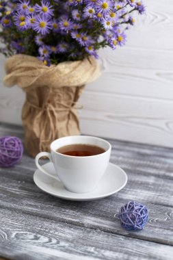 Romantik bir arka plan, bir fincan çay, gri ahşap bir masada vazoda leylak çiçekleri..