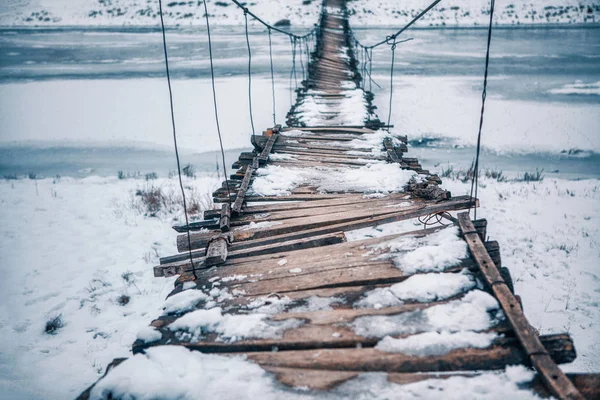 rope bridge broken and covered by snow