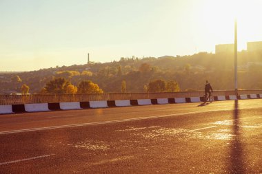 adam güneş ışığı altında köprüde bisikletle
