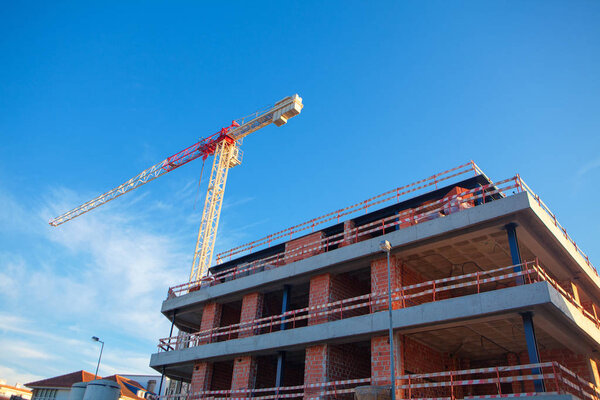 house under construction and crane against blue sky
