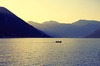 Şafakla birlikte körfezde sakin bir sabah. Gölde dağlarla çevrili bir balıkçı teknesi. Kotor Körfezi 'nin olağanüstü doğası