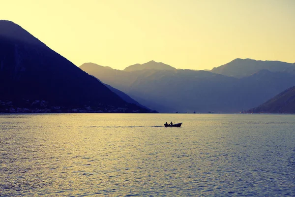 Şafakla birlikte körfezde sakin bir sabah. Gölde dağlarla çevrili bir balıkçı teknesi. Kotor Körfezi 'nin olağanüstü doğası