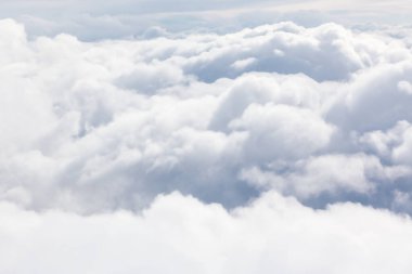 Bir hava manzarası kalın, beyaz bir kabarık bulut katmanı yakalar. Yoğun bulut oluşumları arasında gökyüzü zar zor görünüyor.