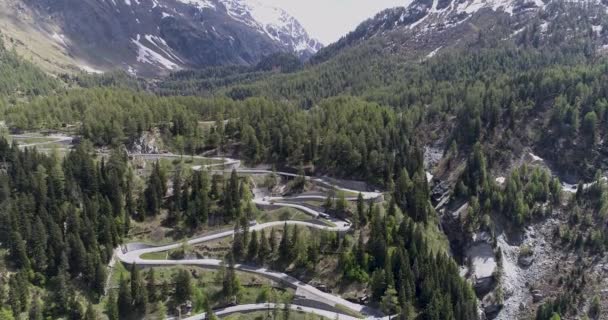 Luchtfoto van serpentijn bergweg met vrachtwagens en auto's rijden op zig zag omhoog en omlaag gaan in Europa Zwitserland 4k — Stockvideo