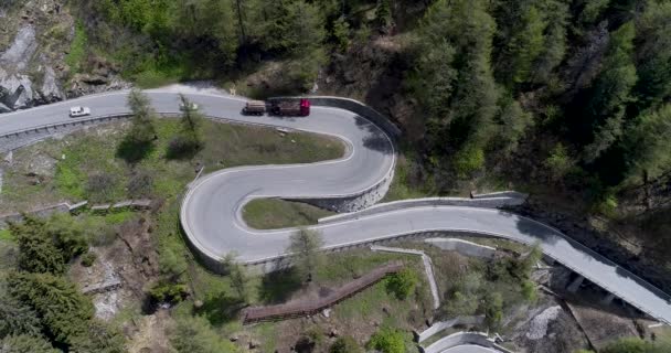 Vista aérea da estrada serpentina de montanha com caminhões e carros dirigindo em zig zag ir para cima e para baixo na Europa Suíça 4K — Vídeo de Stock