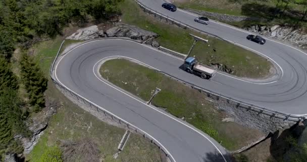 Вид с воздуха на горную змеиную дорогу с грузовиками и автомобилями, движущимися по зигзагу, идет вверх и вниз в Европе Швейцария 4K — стоковое видео