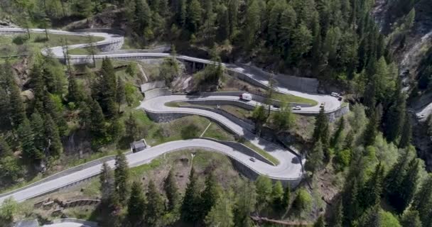 Вид с воздуха на горную змеиную дорогу с грузовиками и автомобилями, движущимися по зигзагу, идет вверх и вниз в Европе Швейцария 4K — стоковое видео
