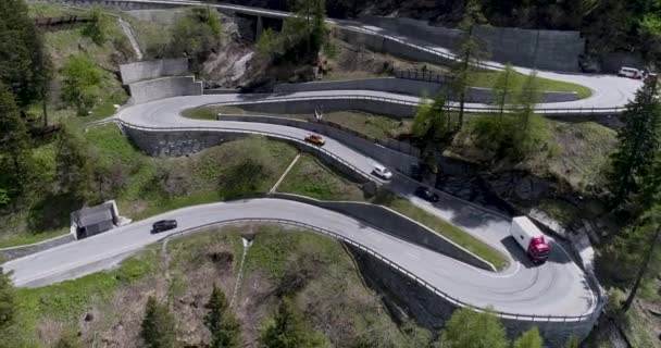 Vista aérea da estrada serpentina de montanha com caminhões e carros dirigindo em zig zag ir para cima e para baixo na Europa Suíça 4K — Vídeo de Stock