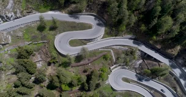 Luchtfoto van serpentijn bergweg met vrachtwagens en auto's rijden op zig zag omhoog en omlaag gaan in Europa Zwitserland 4k — Stockvideo