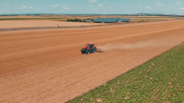 Воздушные беспилотники видят красный трактор, работающий на пшеничном поле. Сельское хозяйство и окружающая среда в Европейском Союзе . — стоковое видео