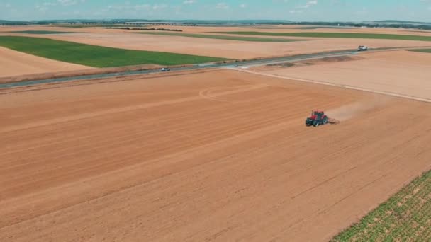 Luftaufnahme eines roten Traktors bei der Arbeit im Weizenfeld. Landwirtschaft und Umwelt in der Europäischen Union.