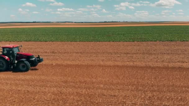 Vista aérea do drone do tracor vermelho que trabalha no campo do trigo. Agricultura e ambiente na União Europeia . — Vídeo de Stock