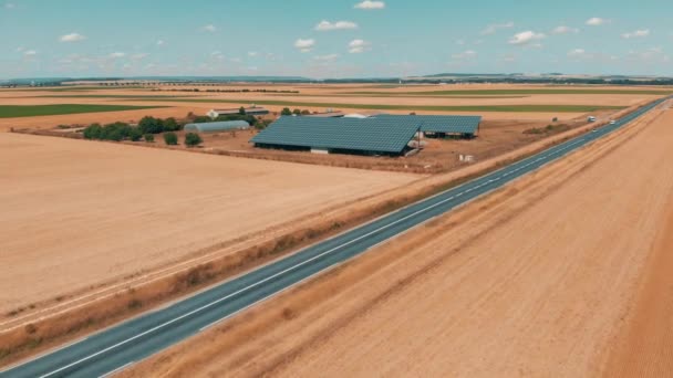 Imágenes aéreas de aviones no tripulados de una pequeña granja de paneles solares y tráfico por carretera — Vídeo de stock
