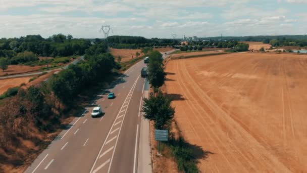 Vista aérea de los coches y camiones que van a la planta de fabricación agrícola industrial y almacén en el campo. Concepto de logística y transporte. Campos de centeno, trigo que rodea la planta — Vídeo de stock