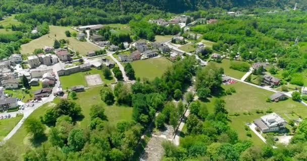Luchtfoto van typische Alpen dorpje in de groene heuvels en dalen van de Alpen in Italië of Oostenrijk in 4k — Stockvideo