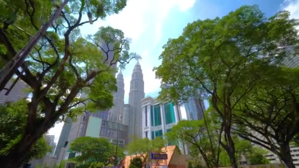 Kuala Lumpur, Malaysia - 15 maj 2018: The Petronas Towers eller Petronas Twin Towers en populära turister attraktion stiga över gröna tropiska träd. 4k — Stockvideo