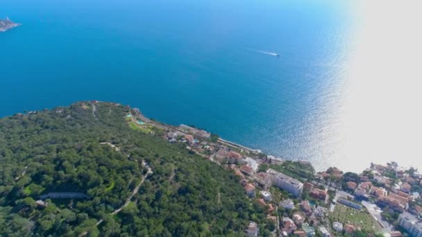 By vid Medelhavet nära Nice bland de gröna kullarna i solsken ljus. hustak och smala gatorna nedanför. bergen och havet i fjärran. Sommaren i Frankrike från 4 k drone Flygfoto — Stockvideo