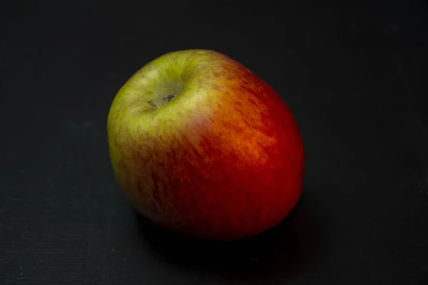 Red Apple on black wooden background. Close up.