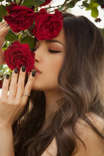 Красивая Молодая Женщина Держит Красные Розы Близко Лицу — стоковое фото