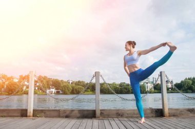 Genç güzel kadın yoga uygulamaları ve nehir dolgu üzerinde derin derin düşünür
