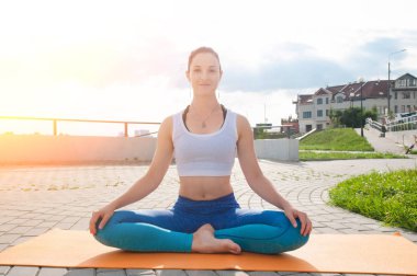 Genç güzel kadın yoga uygulamaları ve nehir dolgu üzerinde derin derin düşünür