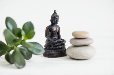 Yeşil yaprakları ve Buda heykeli ile beyaz zen taşlarının piramitler. Uyum, denge ve meditasyon, spa, kavramı masaj, sakin ol