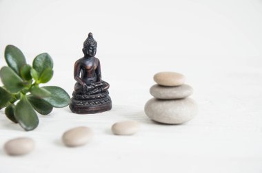 Yeşil yaprakları ve Buda heykeli ile beyaz zen taşlarının piramitler. Uyum, denge ve meditasyon, spa, kavramı masaj, sakin ol