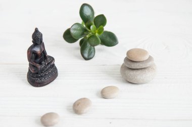 Yeşil yaprakları ve Buda heykeli ile beyaz zen taşlarının piramitler. Uyum, denge ve meditasyon, spa, kavramı masaj, sakin ol