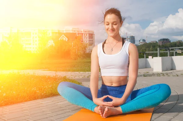 Genç güzel kadın yoga uygulamaları ve nehir dolgu üzerinde derin derin düşünür