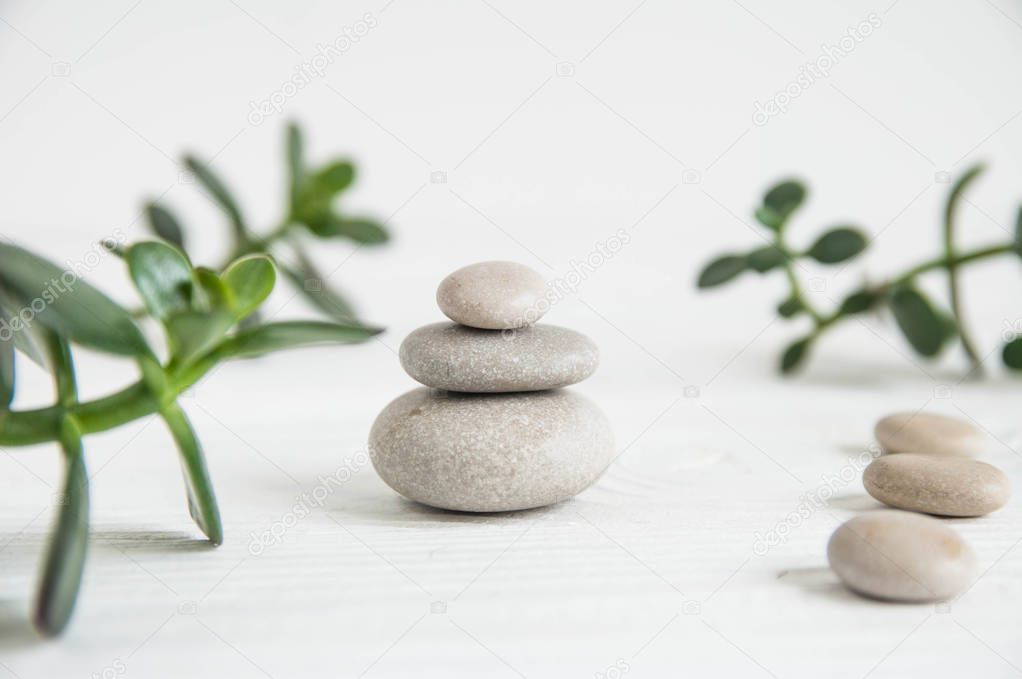 Pyramids of white zen stones with green leaves on wooden background. Concept of harmony, balance and meditation, spa, massage, relax
