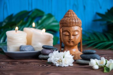 Gri Zen taşlarından piramitler, güzel taze beyaz çiçekler yeşil yapraklar ve ahşap arka planda Buda heykeli. Uyum kavramı, denge ve meditasyon, spa, masaj, rahatlama