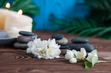 Gri Zen taşlarından piramitler, güzel taze beyaz çiçekler yeşil yapraklar ve ahşap arka planda Buda heykeli. Uyum kavramı, denge ve meditasyon, spa, masaj, rahatlama