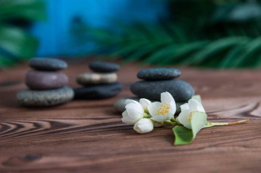 Gri Zen taşlarından piramitler, güzel taze beyaz çiçekler, ahşap arka planda yeşil yapraklar. Uyum kavramı, denge ve meditasyon, spa, masaj, rahatlama