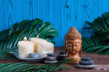 Gri Zen taşlarından piramitler, güzel taze beyaz çiçekler yeşil yapraklar ve ahşap arka planda Buda heykeli. Uyum kavramı, denge ve meditasyon, spa, masaj, rahatlama