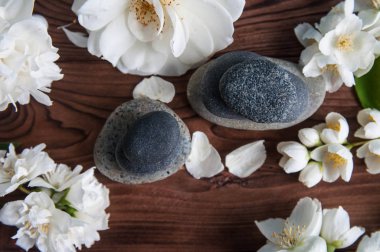 Gri Zen taşlarından piramitler, güzel taze beyaz çiçekler, ahşap arka planda yeşil yapraklar. Uyum kavramı, denge ve meditasyon, spa, masaj, rahatlama